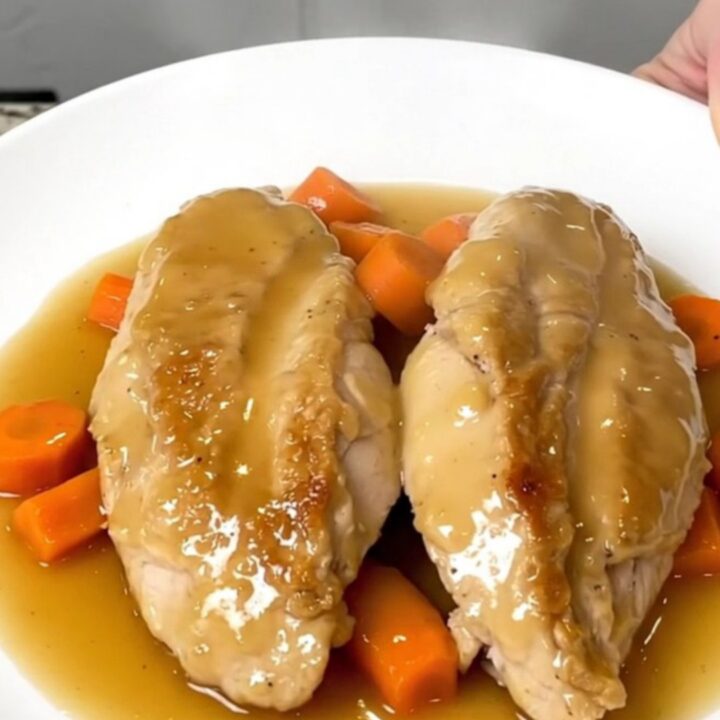 A white plate featuring tender honey ginger chicken breasts topped with glazed carrot coins.