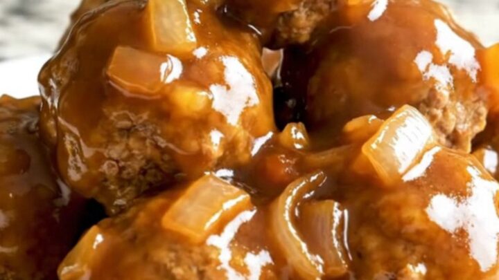 A slow cooker filled with glazed apricot barbecue turkey meatballs topped with diced onions and herbs.