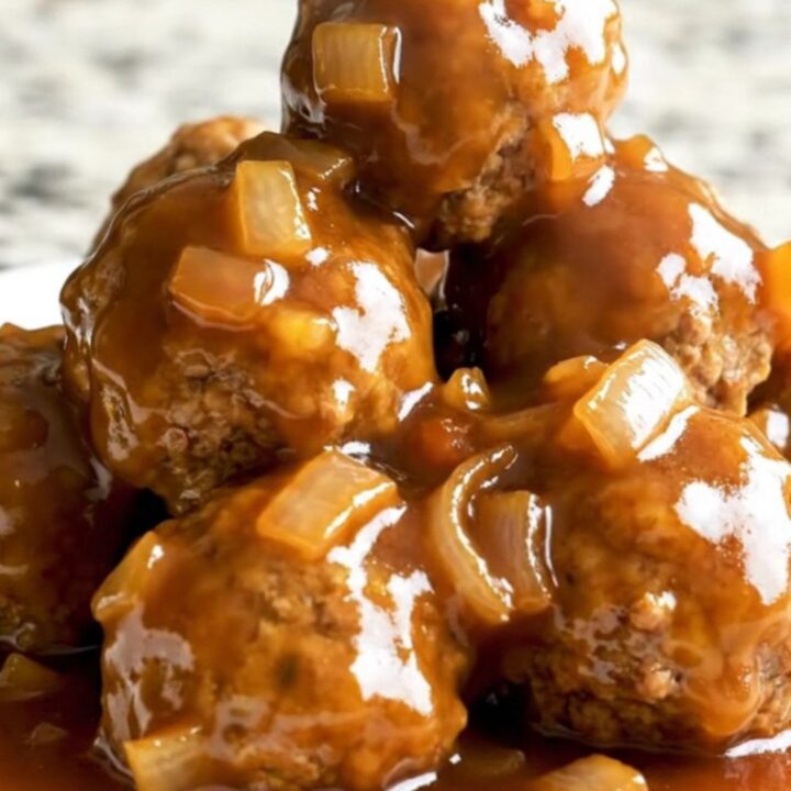 A slow cooker filled with glazed apricot barbecue turkey meatballs topped with diced onions and herbs.
