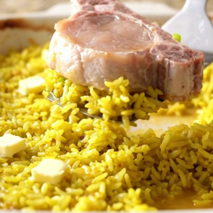 A top-down view of a rectangular baking dish filled with yellow rice and tender boneless pork chops.