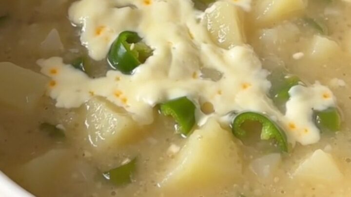 A warm bowl of creamy green chile potato soup with visible potato chunks and melted cheese.