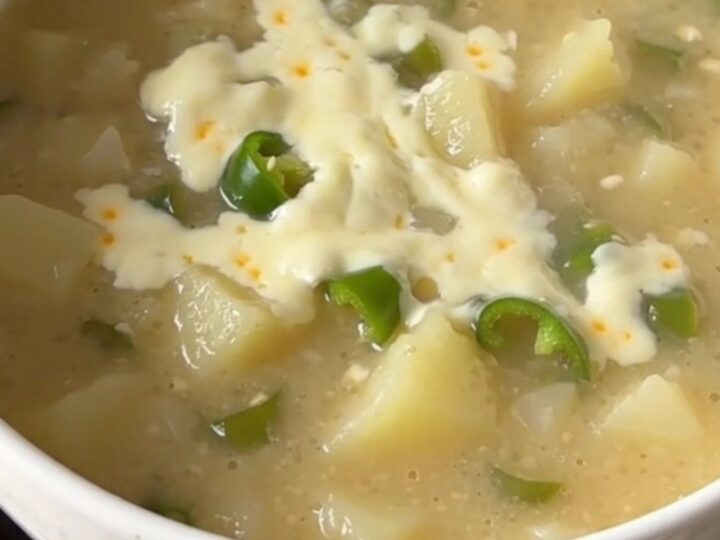 A warm bowl of creamy green chile potato soup with visible potato chunks and melted cheese.