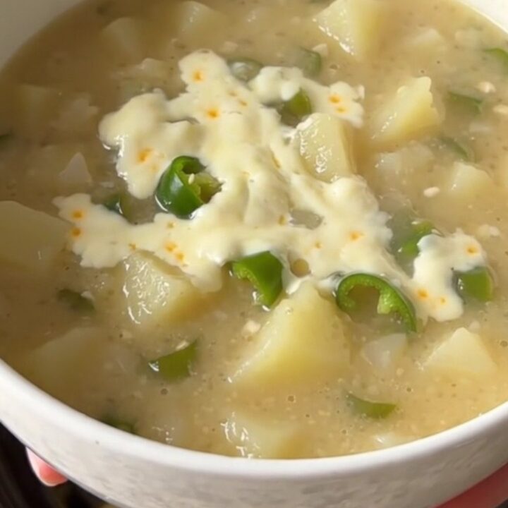 A warm bowl of creamy green chile potato soup with visible potato chunks and melted cheese.