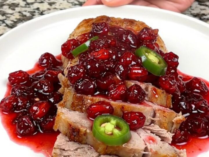 A close-up of sliced cranberry jalapeno pork tenderloin on a white plate.