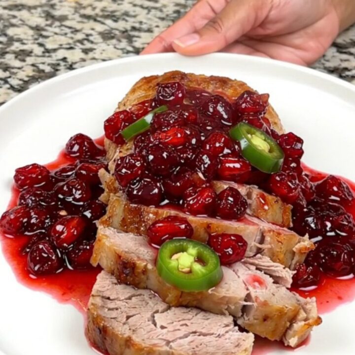 A close-up of sliced cranberry jalapeno pork tenderloin on a white plate.