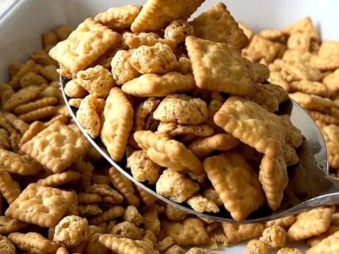 A large rectangular baker filled with a golden, toasted garlic parmesan snack mix on a white countertop.