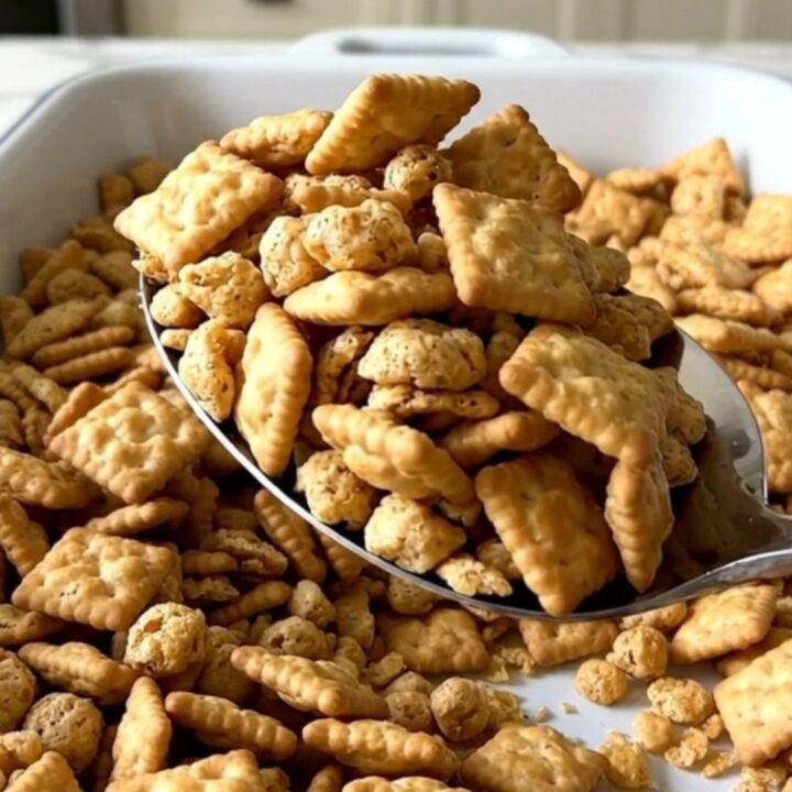 A large rectangular baker filled with a golden, toasted garlic parmesan snack mix on a white countertop.