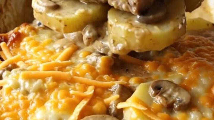 A ceramic baking dish filled with tender pork chops, sliced potatoes, and creamy mushroom sauce topped with melted cheddar.