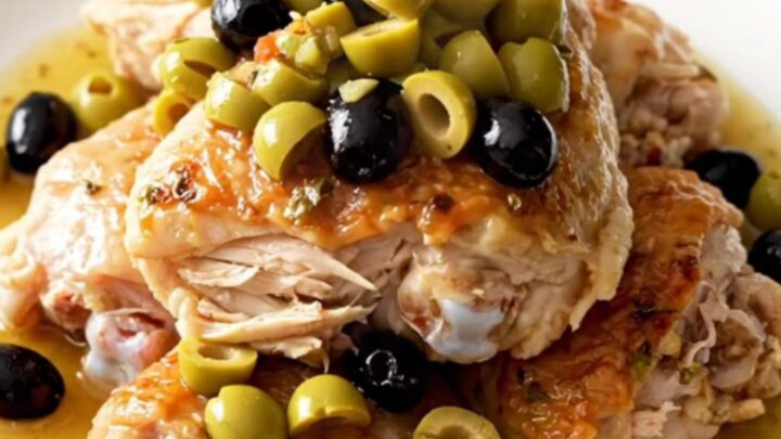 A top-down view of slow cooker muffuletta chicken with visible pieces of olive salad and fresh herbs.