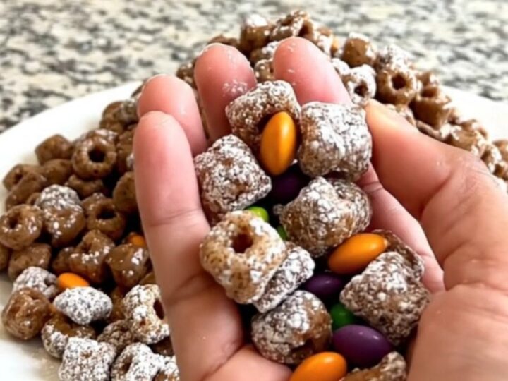 A top-down view of Halloween puppy chow spread on a dark baking sheet