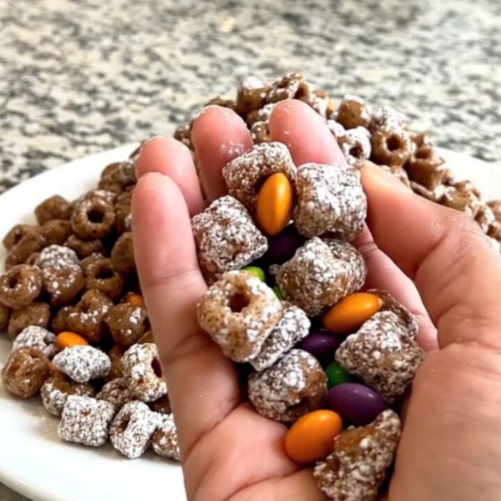 A top-down view of Halloween puppy chow spread on a dark baking sheet