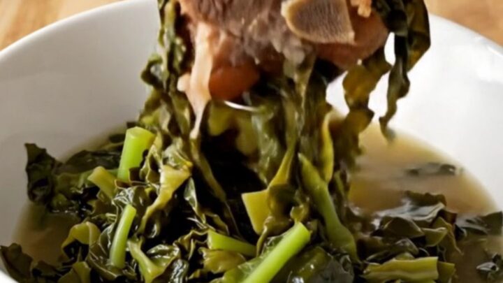 A slow cooker filled with tender collard greens and savory ham hocks, ready to be served as a classic side dish.