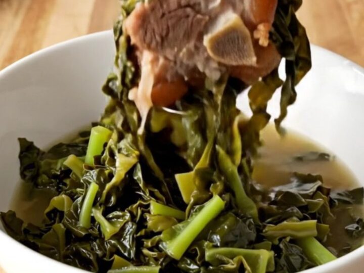A slow cooker filled with tender collard greens and savory ham hocks, ready to be served as a classic side dish.