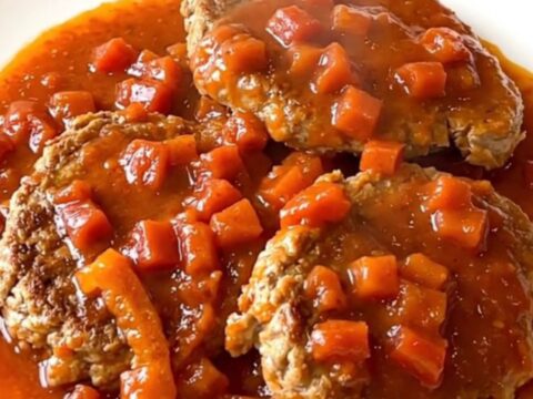 A close-up of smoky turkey burger steaks in a slow cooker topped with fire-roasted tomatoes and peppers.
