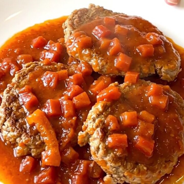 A close-up of smoky turkey burger steaks in a slow cooker topped with fire-roasted tomatoes and peppers.