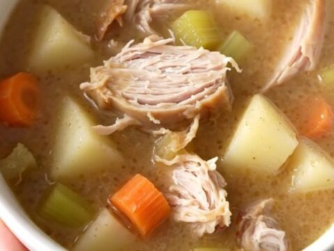 A warm bowl of creamy turkey and gravy potato soup with visible chunks of turkey and vegetables.