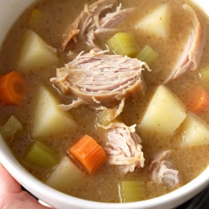 A warm bowl of creamy turkey and gravy potato soup with visible chunks of turkey and vegetables.