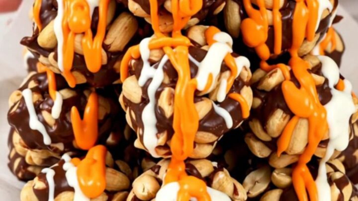 A top-down view of roasted peanuts, chocolate chips, and candy melts inside a black slow cooker insert.
