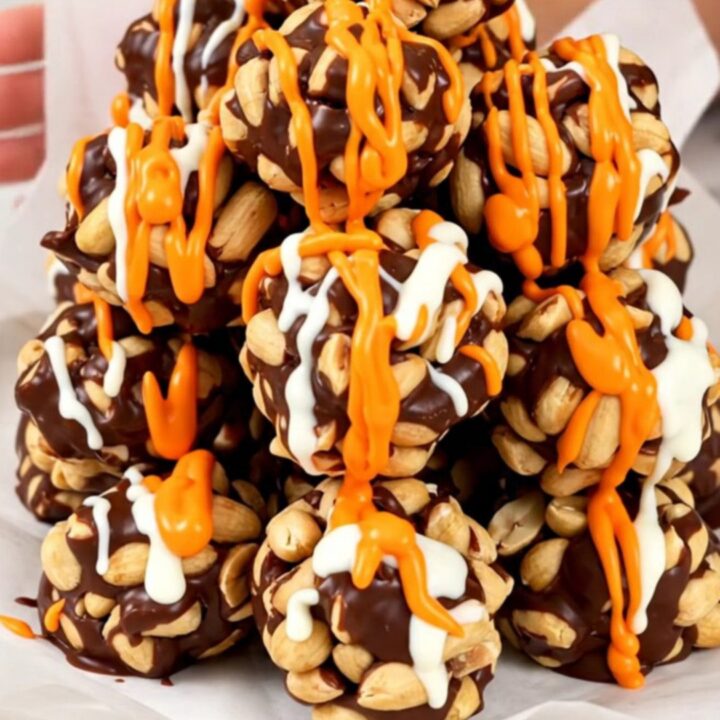 A top-down view of roasted peanuts, chocolate chips, and candy melts inside a black slow cooker insert.