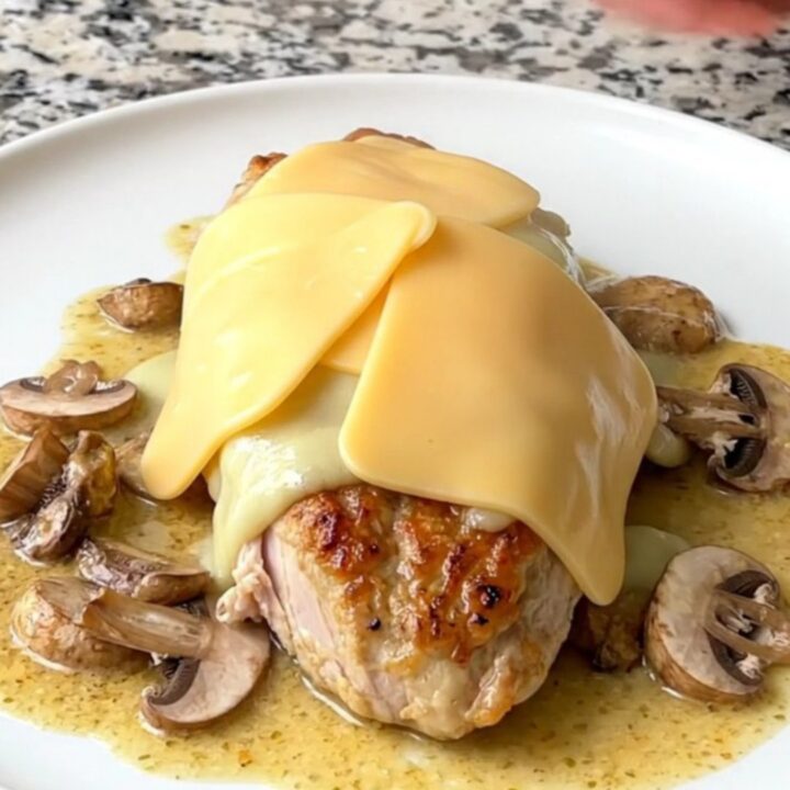 A finished plate of creamy provolone mushroom chicken with a rich, white sauce and melted cheese.