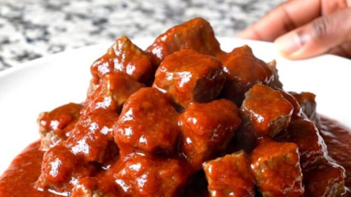 A close-up of tender beef tips in a thick, glossy red gochujang sauce served in a slow cooker insert.