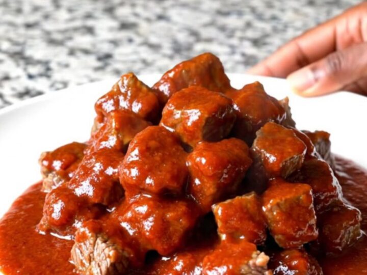 A close-up of tender beef tips in a thick, glossy red gochujang sauce served in a slow cooker insert.