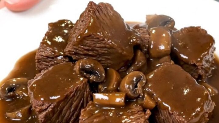A rustic slow cooker filled with tender beef cubes and mushrooms in a rich Marsala sauce.