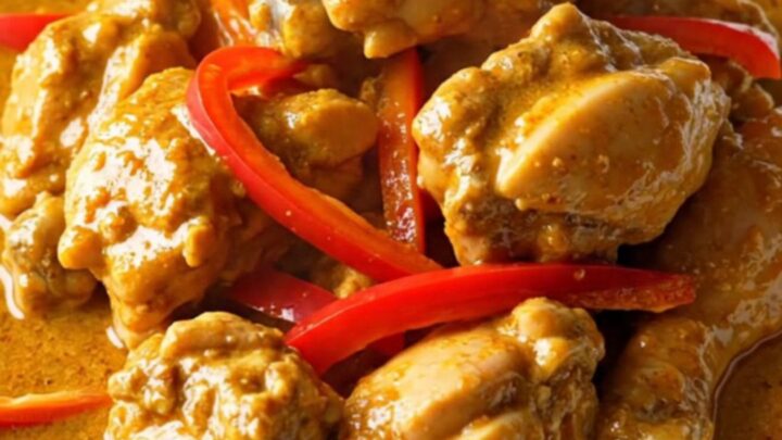 A bowl of creamy Panang chicken curry with red pepper strips served over jasmine rice.