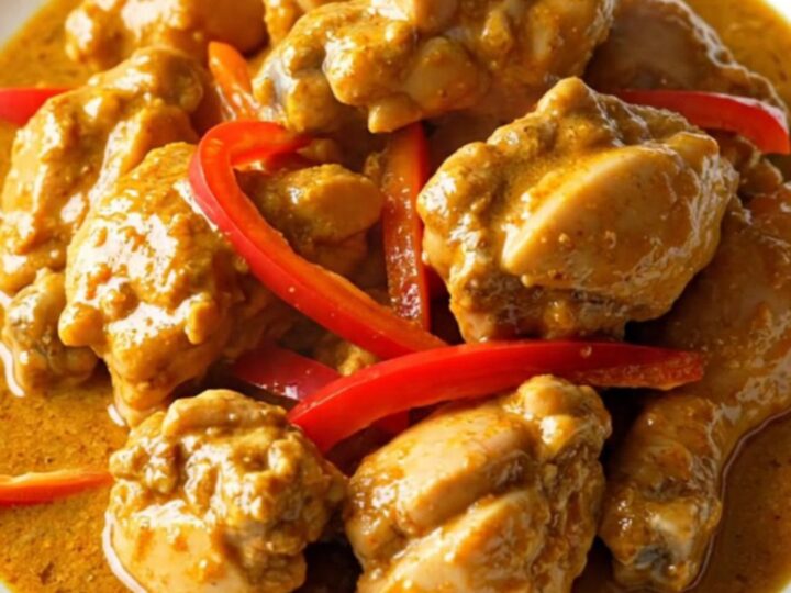 A bowl of creamy Panang chicken curry with red pepper strips served over jasmine rice.