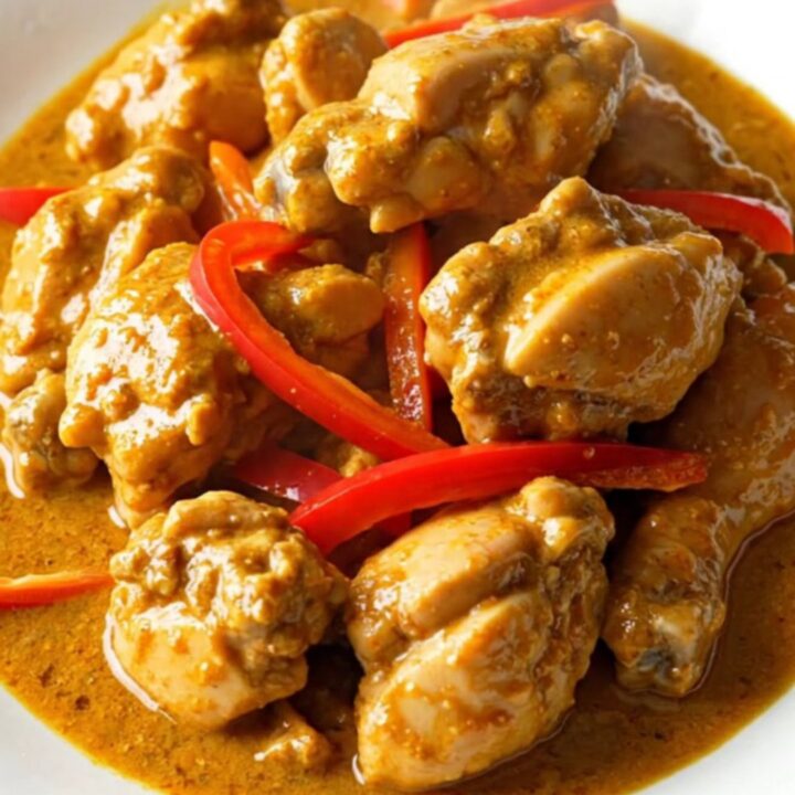 A bowl of creamy Panang chicken curry with red pepper strips served over jasmine rice.