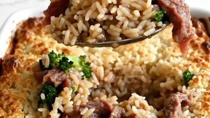 A top-down view of a rectangular ceramic baking dish filled with rice, raw beef strips, and broccoli.