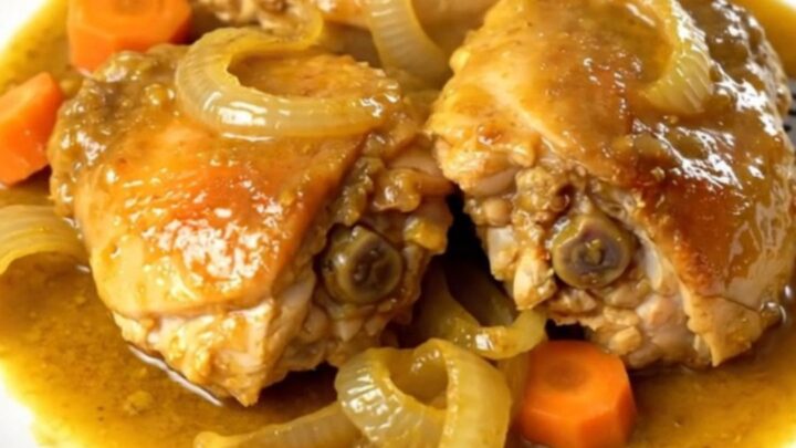 A top-down view of golden turmeric ginger chicken with carrots and onions in a slow cooker.