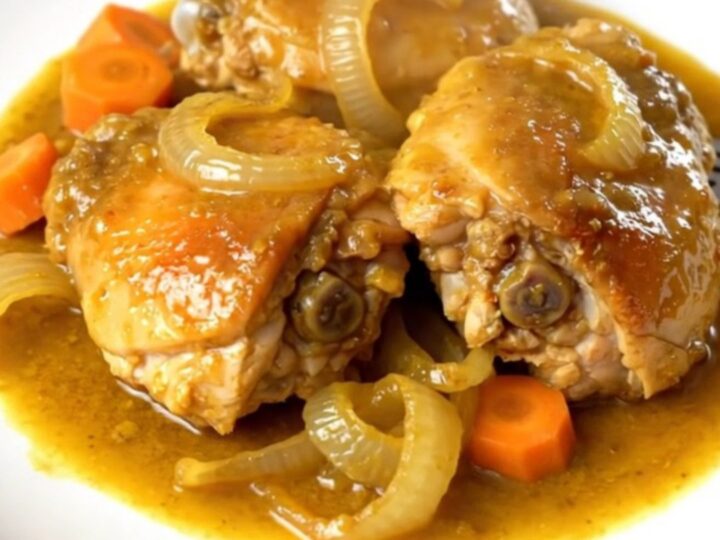 A top-down view of golden turmeric ginger chicken with carrots and onions in a slow cooker.