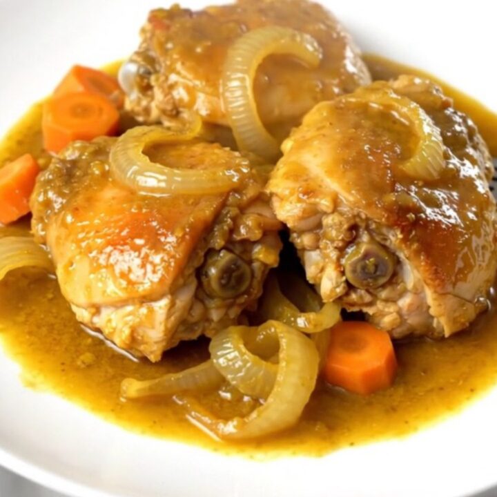 A top-down view of golden turmeric ginger chicken with carrots and onions in a slow cooker.