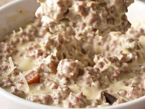Creamy sausage stuffed mushroom dip in a slow cooker with crackers on the side.