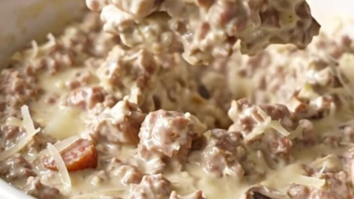 Creamy sausage stuffed mushroom dip in a slow cooker with crackers on the side.