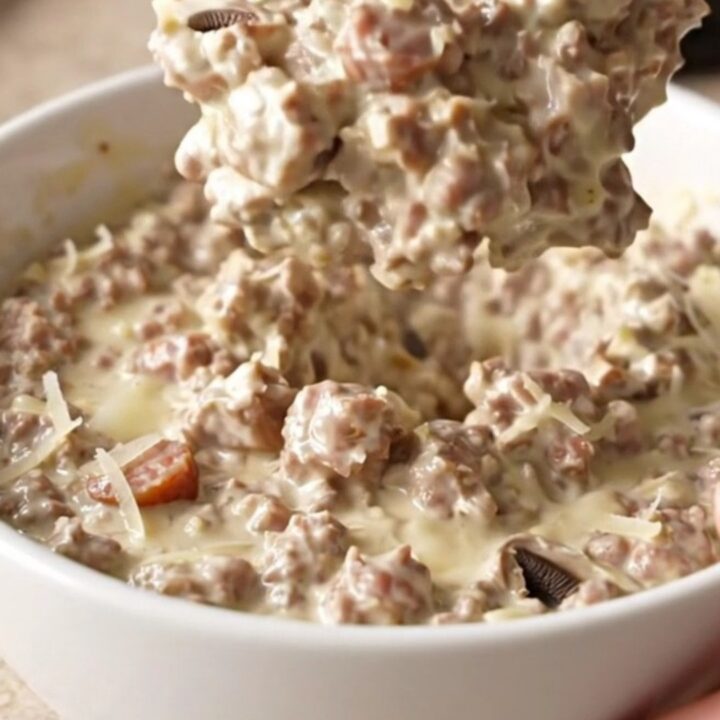 Creamy sausage stuffed mushroom dip in a slow cooker with crackers on the side.