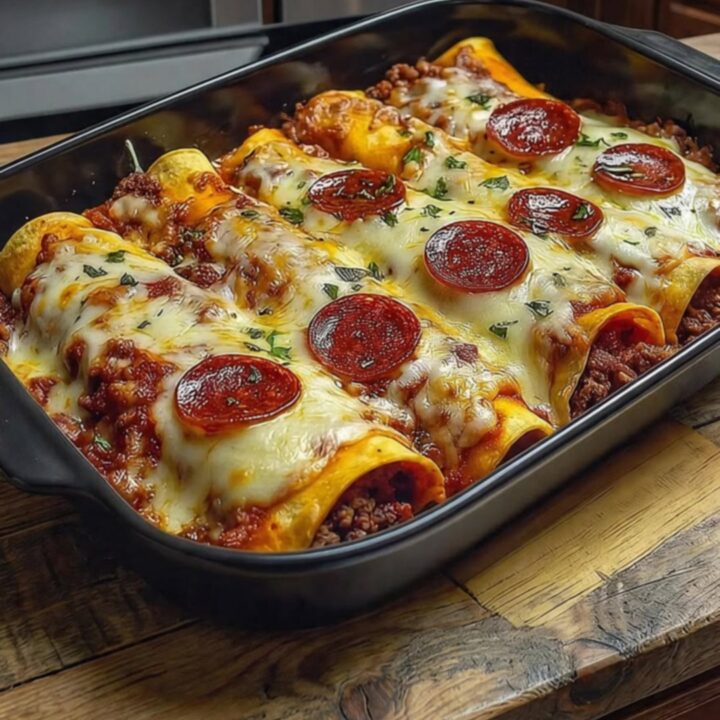 A close-up shot of a spatula lifting a cheesy, pepperoni-topped enchilada from a black casserole dish.
