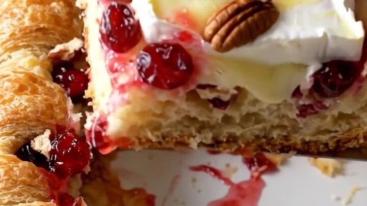 A rectangular baker filled with a golden, flaky cranberry brie crescent bake on a beige countertop.