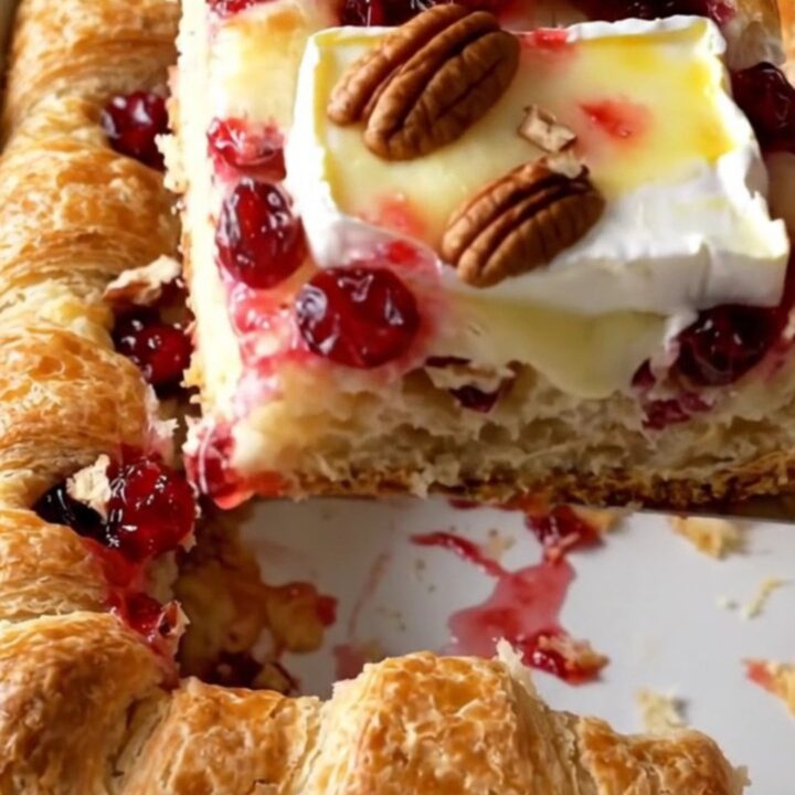 A rectangular baker filled with a golden, flaky cranberry brie crescent bake on a beige countertop.