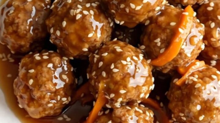 A high-angle shot of frozen turkey meatballs and shredded carrots in a black slow cooker.