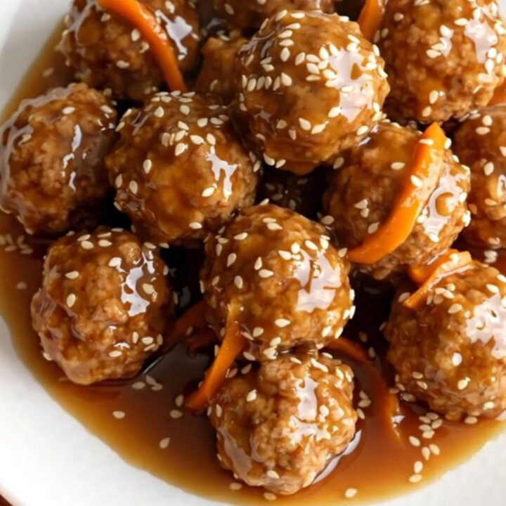 A high-angle shot of frozen turkey meatballs and shredded carrots in a black slow cooker.
