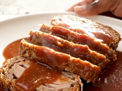 A thick slice of turkey meatloaf covered in a glossy, dark brown sugar and ketchup glaze on a white plate.
