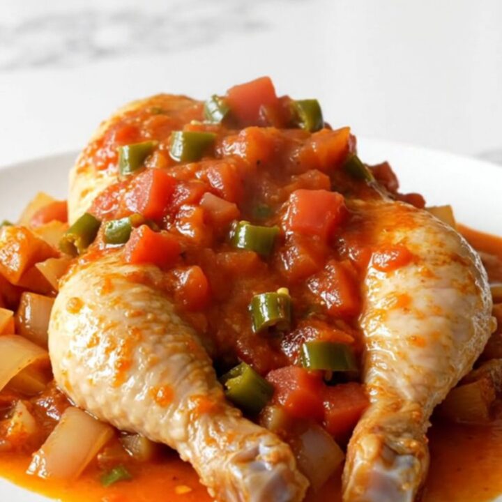 A top-down view of a slow cooker filled with chicken breasts, cubed sweet potatoes, red onion, and a rich tomato sauce.