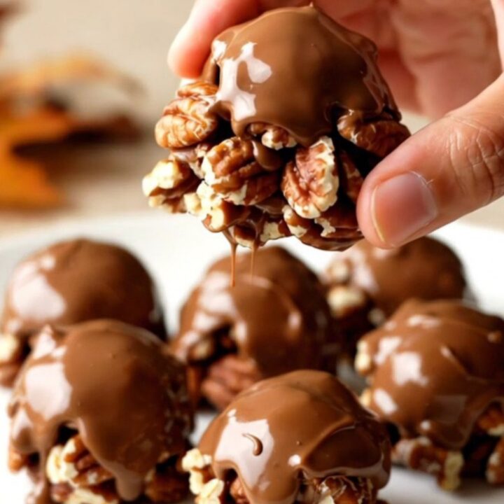 A close-up of finished Turtle Pecan Clusters showing the layered pecan, caramel, and chocolate on a white plate.