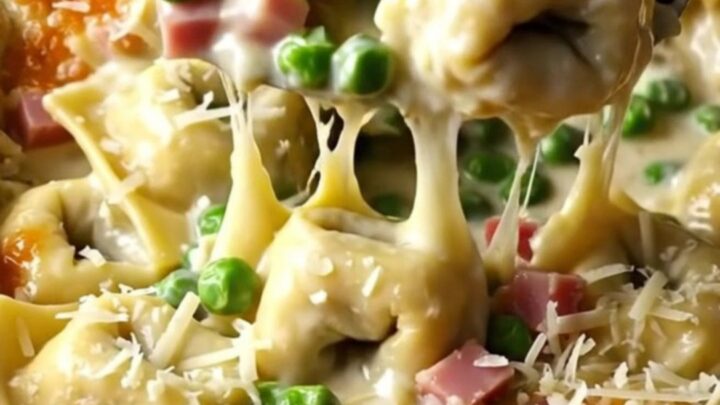A top-down view of a creamy tortellini bake in a white ceramic dish, ready for the oven.