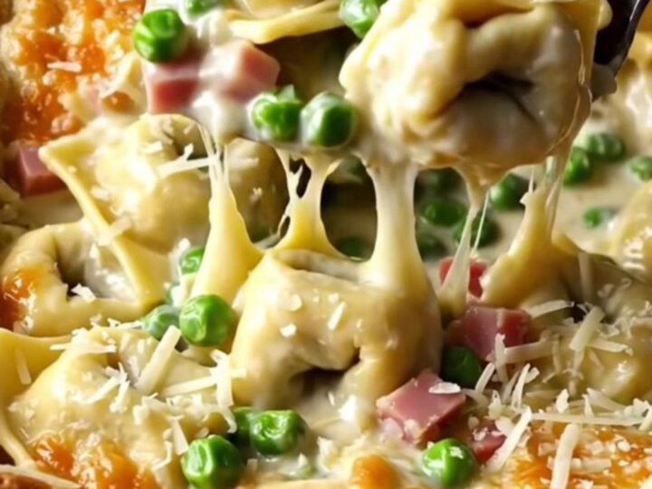 A top-down view of a creamy tortellini bake in a white ceramic dish, ready for the oven.