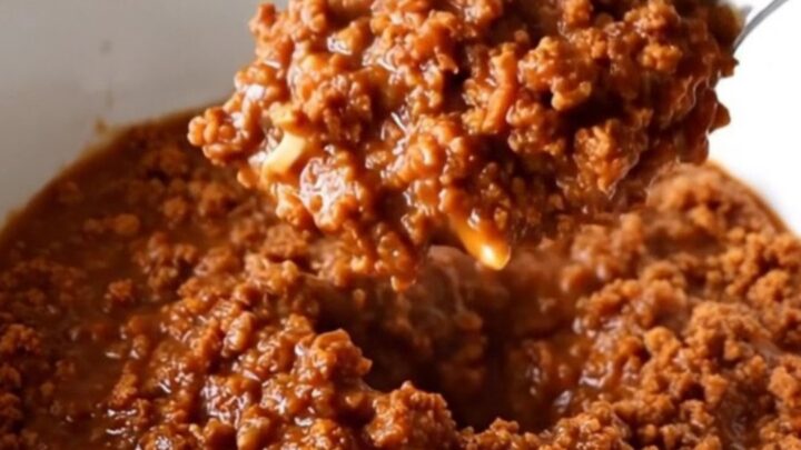 A stainless steel slow cooker filled with a rich, thick, and savory ground turkey chili sauce.