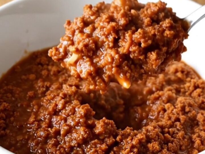 A stainless steel slow cooker filled with a rich, thick, and savory ground turkey chili sauce.