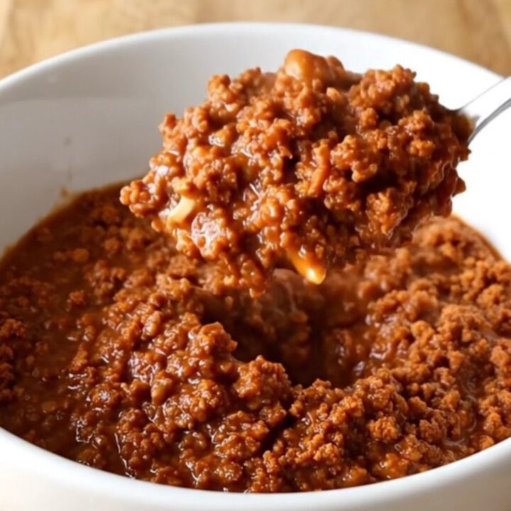 A stainless steel slow cooker filled with a rich, thick, and savory ground turkey chili sauce.